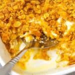 A serving spoon rests in a casserole dish topped with a crunchy golden crust.