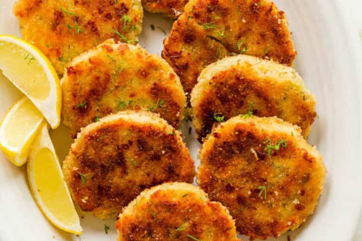 Eight golden-brown chicken patties arranged on a white plate with three lemon wedges on the side—an easy dinner recipe perfect for budget friendly dinners.