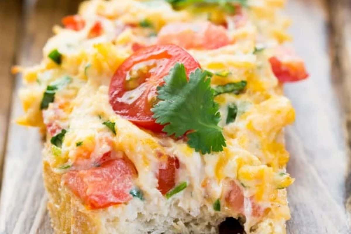A slice of bread topped with melted cheese, chicken, chopped tomatoes, herbs, and a sprig of cilantro—an easy dinner idea that's perfect for budget friendly dinners.