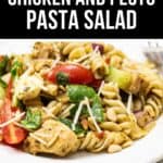 A plate of Chicken and Pesto Pasta Salad with cherry tomatoes, spinach, pine nuts, and shredded cheese.