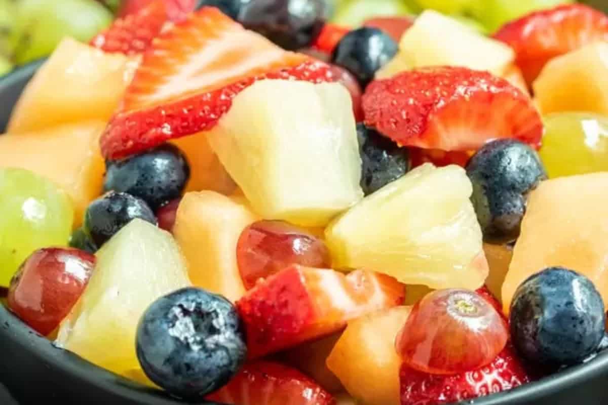 A close-up of a delicious fruit salad containing strawberries, blueberries, pineapple, cantaloupe, green grapes, and red grapes—perfect inspiration for beautiful fruit salads.