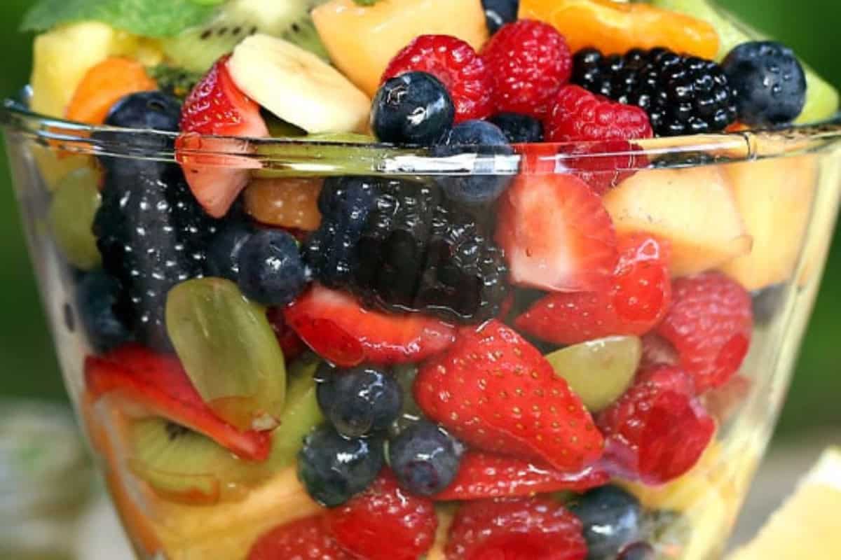 A clear glass bowl filled with a colorful assortment of fresh mixed fruits, this delicious fruit salad features strawberries, blueberries, raspberries, blackberries, kiwi, grapes, and melon—a perfect example of beautiful fruit salads.