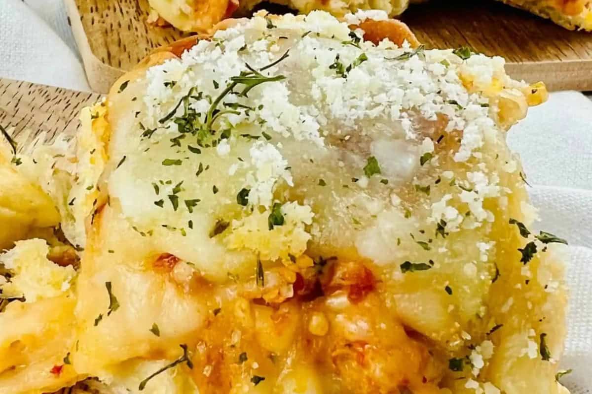 Close-up of a cheesy, baked pastry topped with grated cheese and herbs, inspired by Homemade Italian Recipes, resting on a wooden surface.