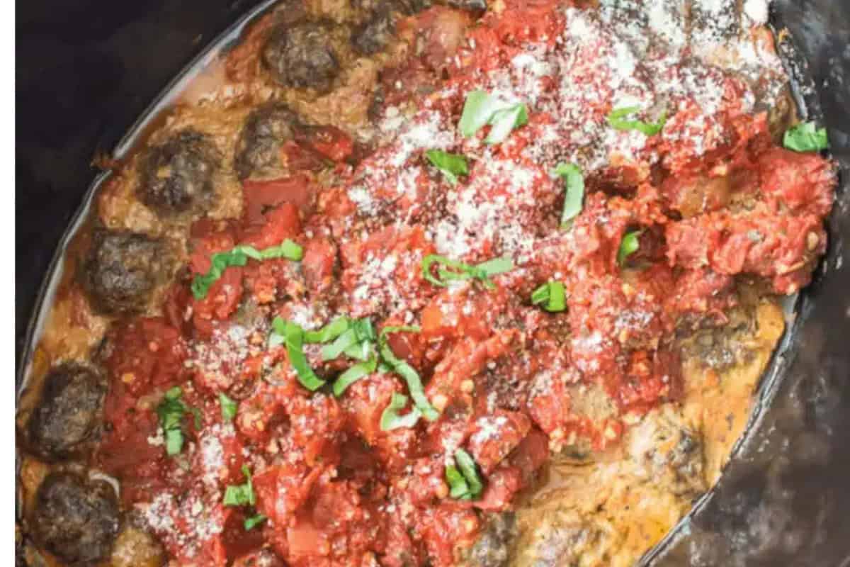Meatballs in marinara sauce topped with grated cheese and fresh basil, served in a slow cooker—a comforting favorite inspired by Homemade Italian recipes.