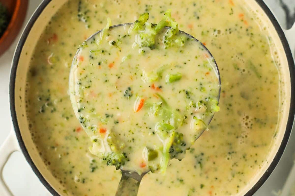 Close-up of a pot of cottage cheese broccoli cheddar soup, ready to be served with a large serving spoon.
