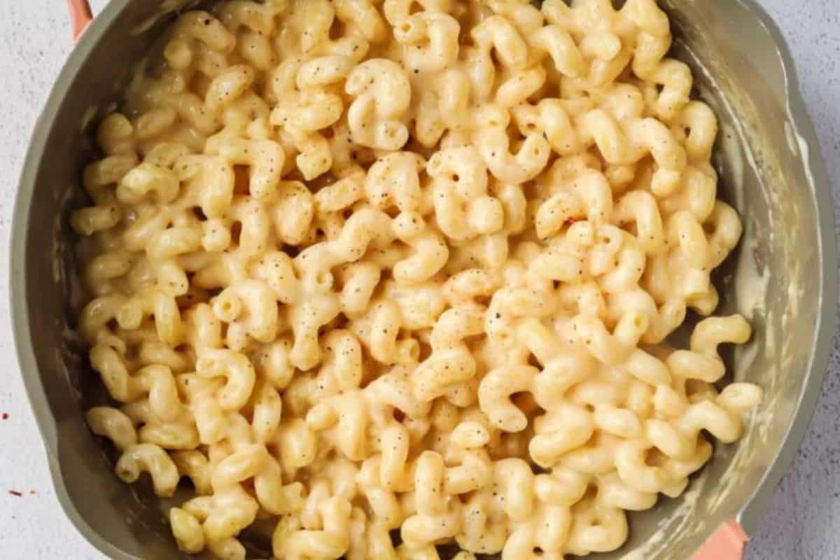 Close-up of a green pot of noodles, smothered in a creamy cottage cheese mac and cheese sauce.