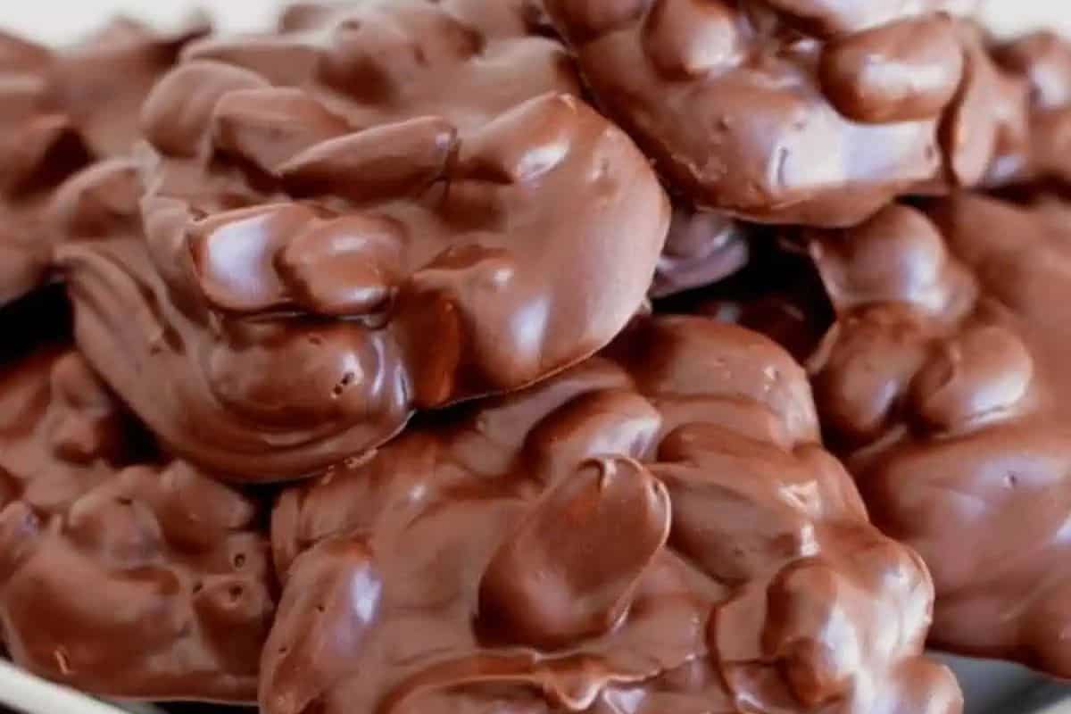 A close-up of several clusters of chocolate-covered nuts stacked together, showcasing one of the most effortless desserts perfect for any Slow Cooker Desserts lineup.