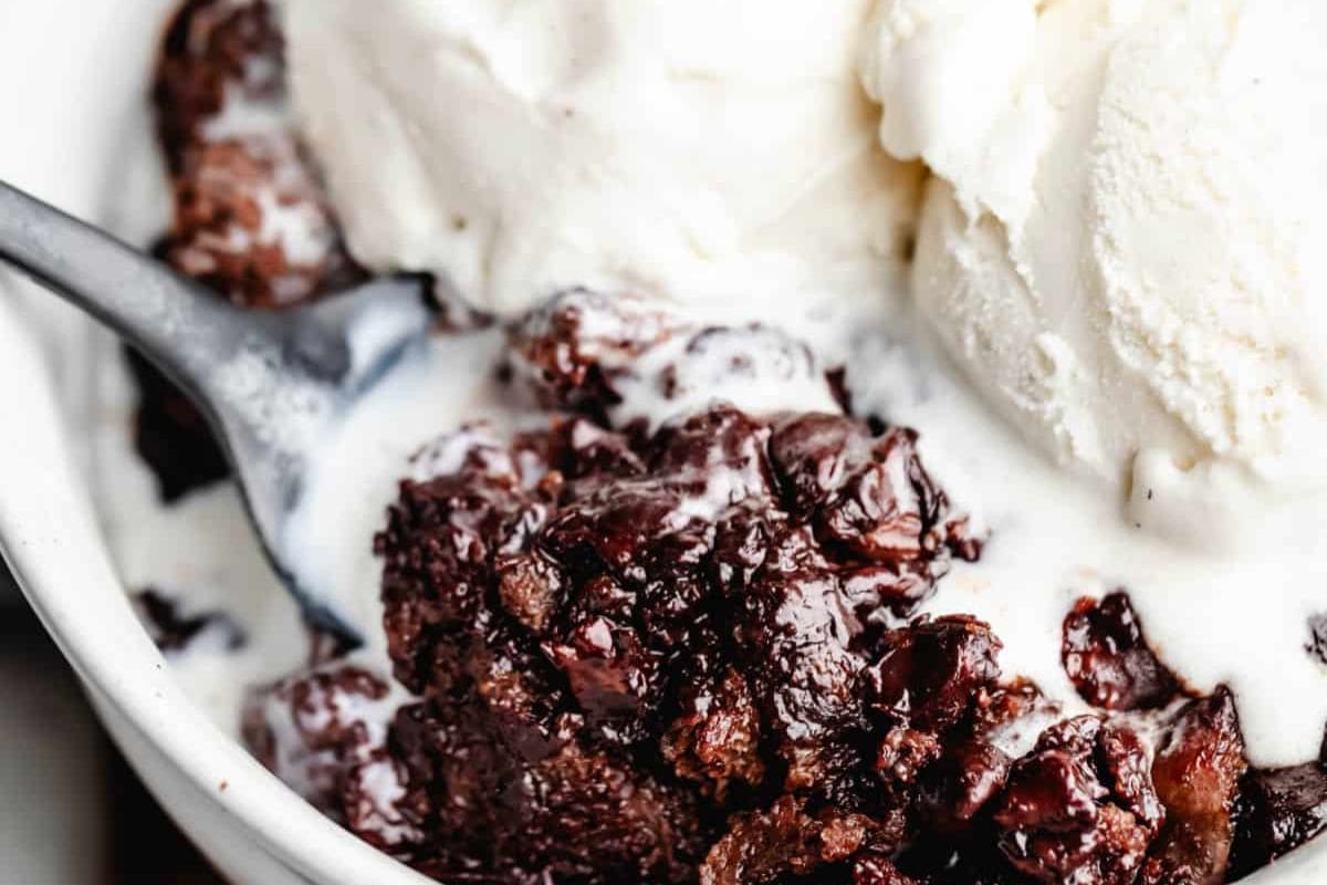Close-up of a bowl with chocolate bread pudding and melting vanilla ice cream, showcasing an effortless indulgence that makes Crock Pot Desserts irresistible; a spoon is partially visible.