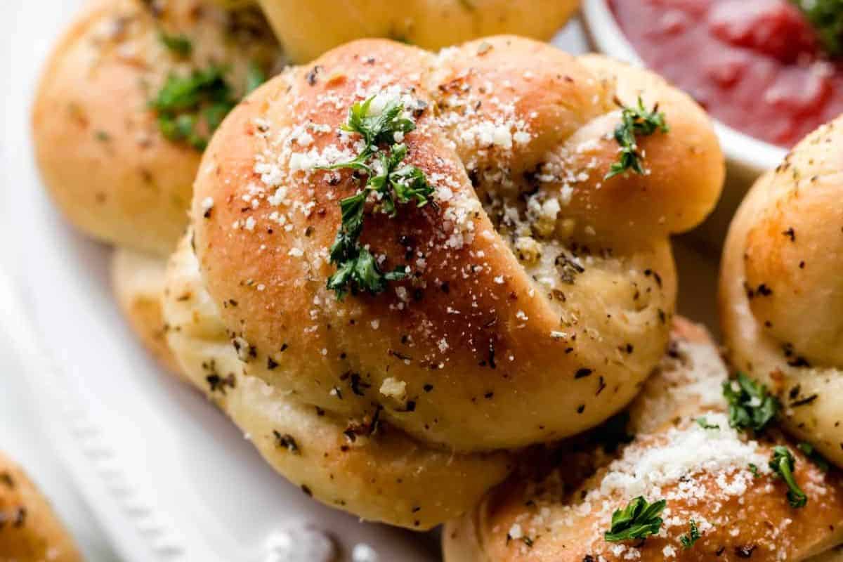 Close-up of some homemade garlic knots, crusted with parmesan cheese and parsley. 