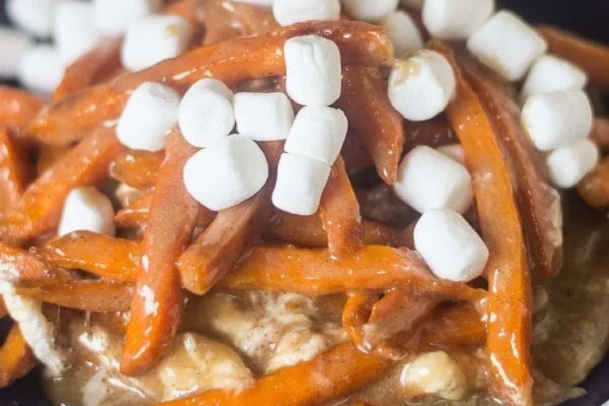 A close-up of sweet potato fries topped with mini marshmallows and caramel sauce, delivering crazy good flavor and a fun twist on classic French fry recipes.
