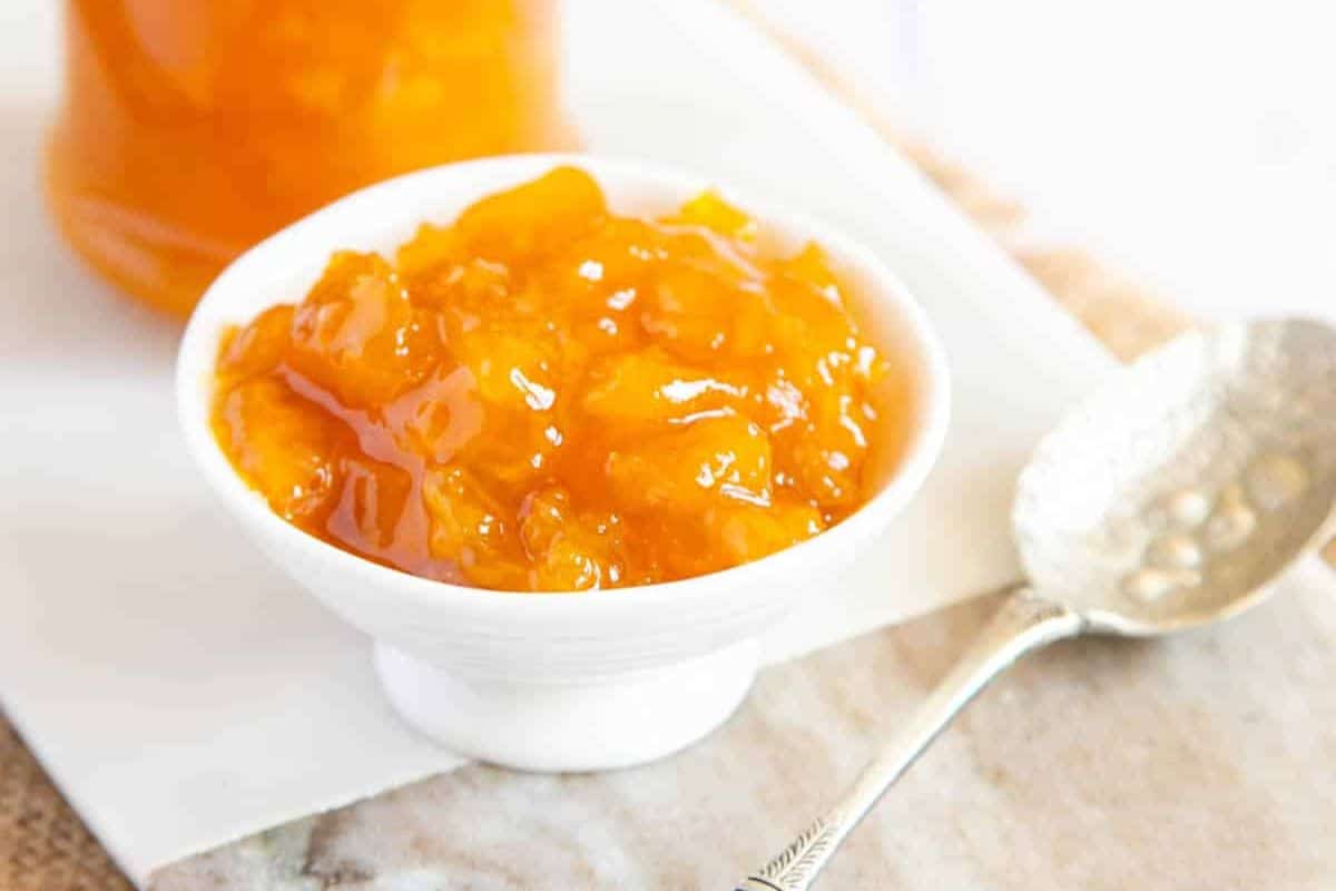 A close-up of a white bowl of mango jam.