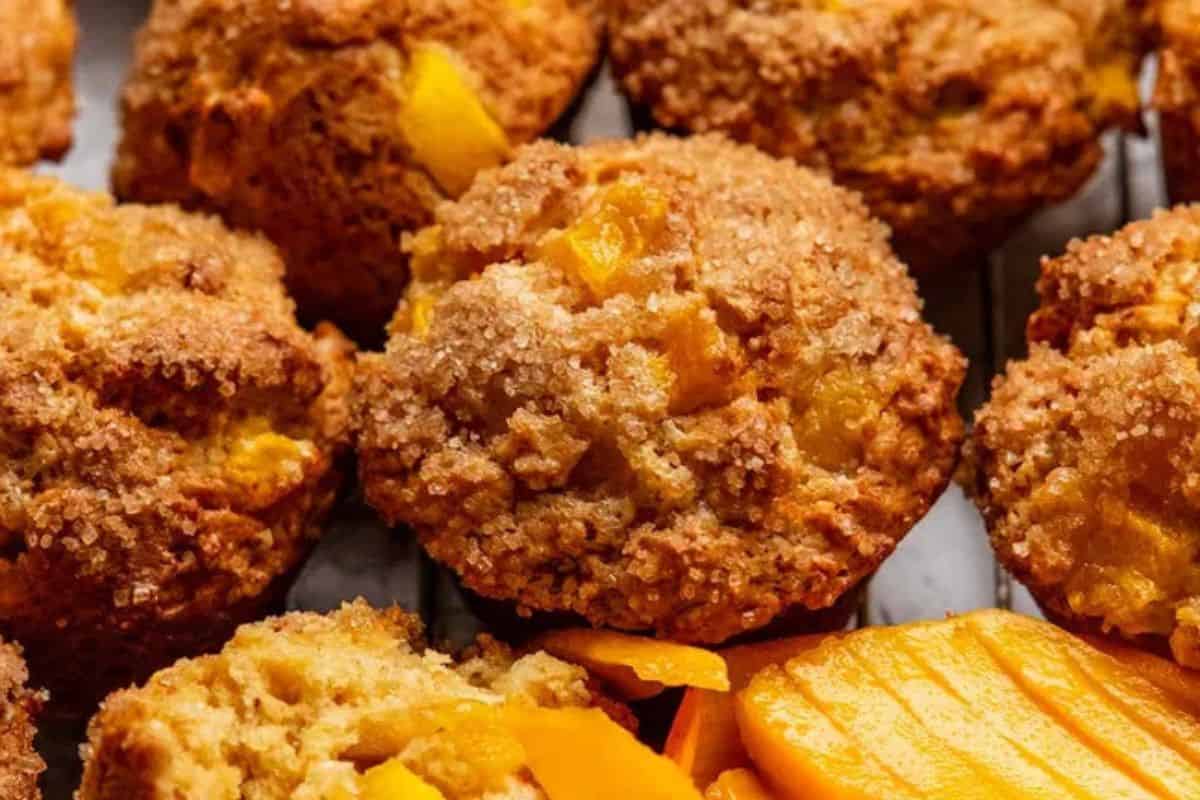 A close-up of some mango muffins, served with some sliced mangos on the side.