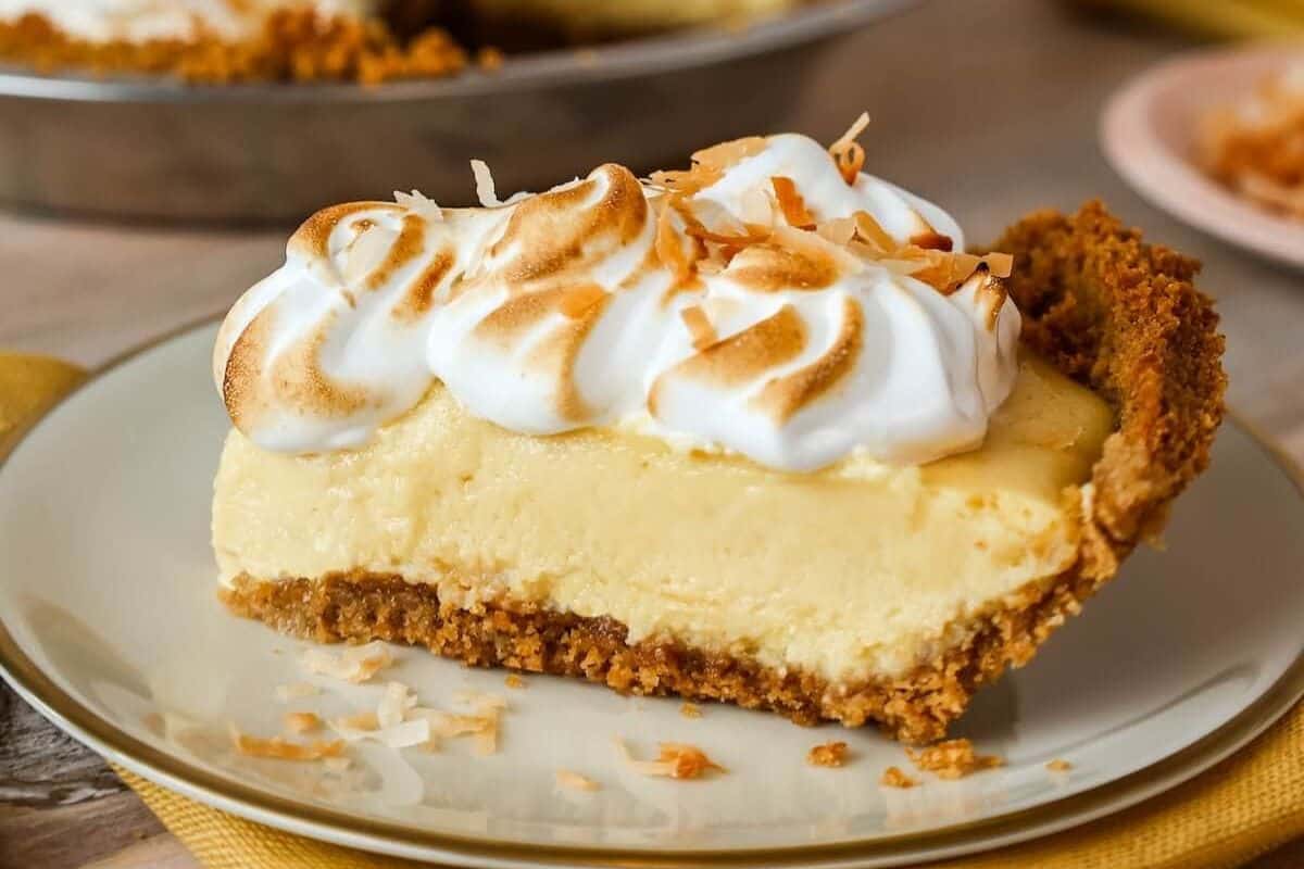 A close-up of a slice of coconut mango pie, served on a tan plate.