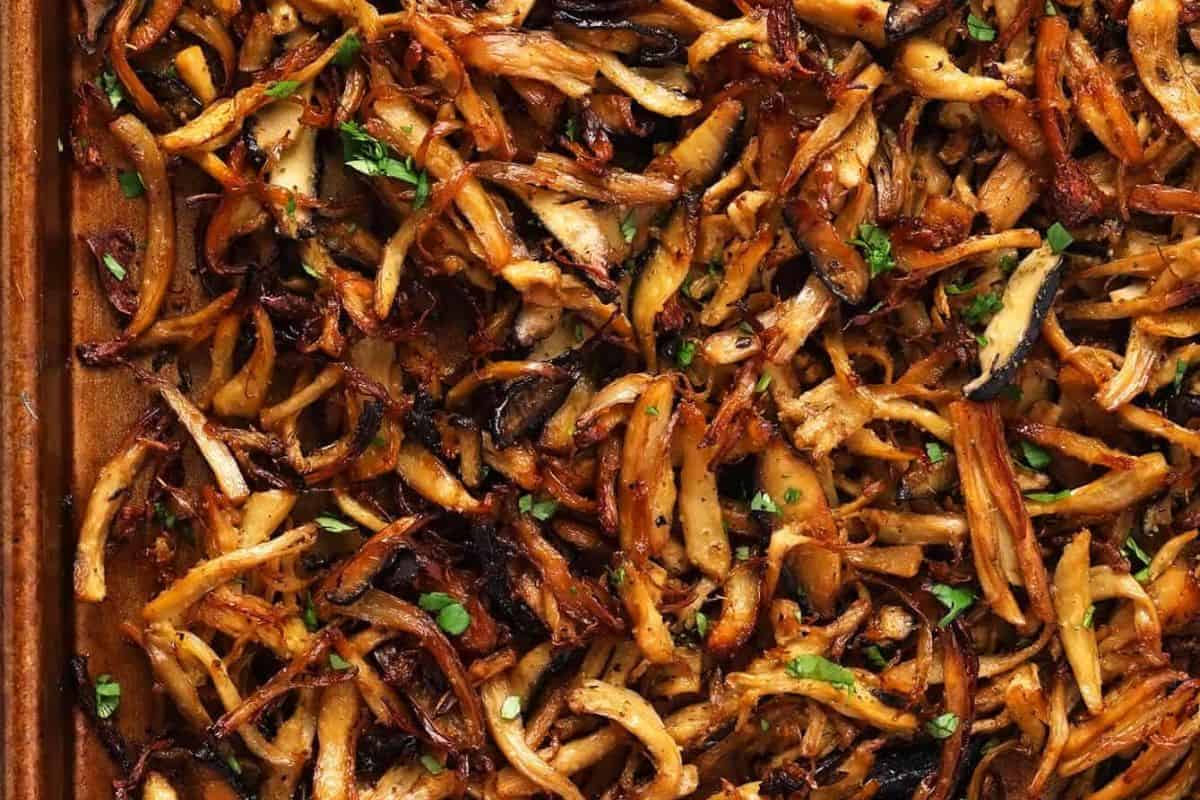 Close-up of roasted, shredded mushrooms with browned, crispy edges and small bits of chopped herbs on top—a must try for anyone looking to go beyond the basics of mushroom dishes.