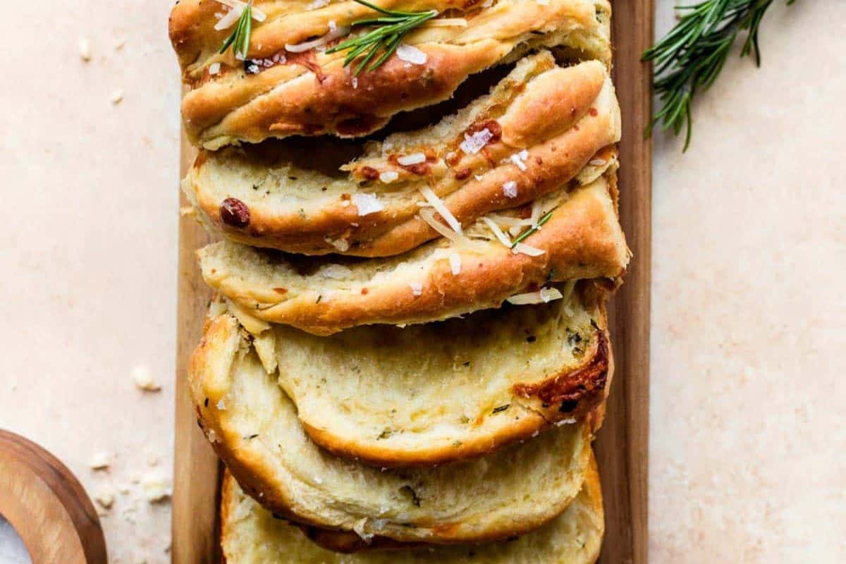 Close-up of a loaf of cheesy garlic pull apart bread, served on a wooden cutting board.