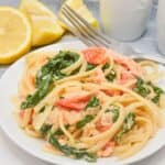 A delicious plate of salmon pasta with lemon on the side.