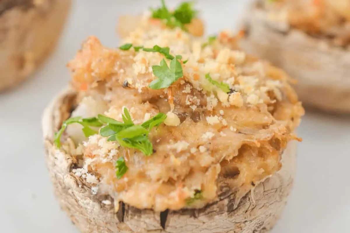 Close-up of a stuffed mushroom cap topped with a creamy filling, breadcrumbs, and chopped fresh parsley—this must try dish takes mushroom dishes beyond the basics.