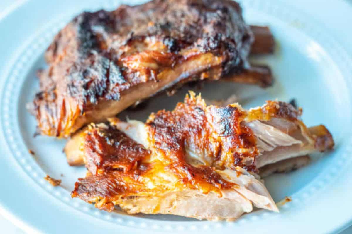 A close-up of some slow cooker Coca-Cola ribs, served on a light blue plate.