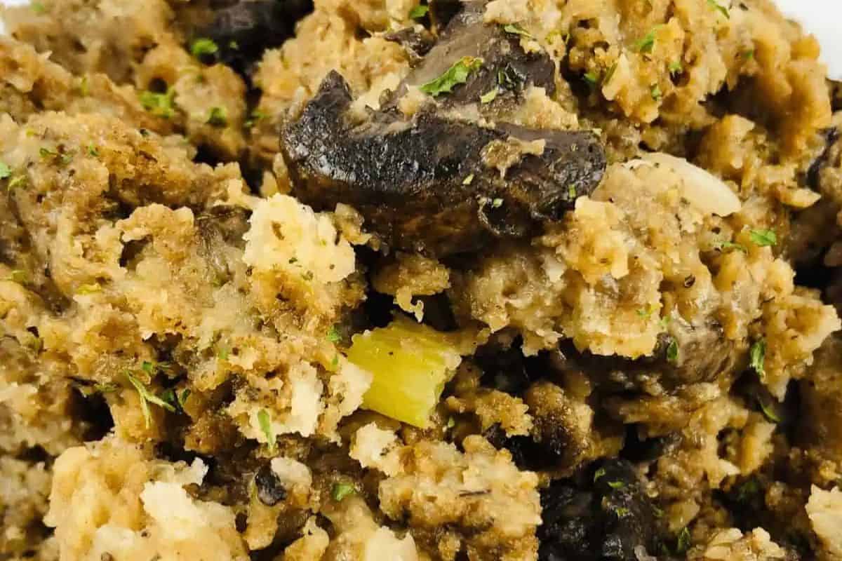 Close-up of a dish featuring moist bread stuffing mixed with chunks of mushrooms, celery, herbs, and seasonings—a must try for anyone looking to go beyond the basics with classic mushroom dishes.