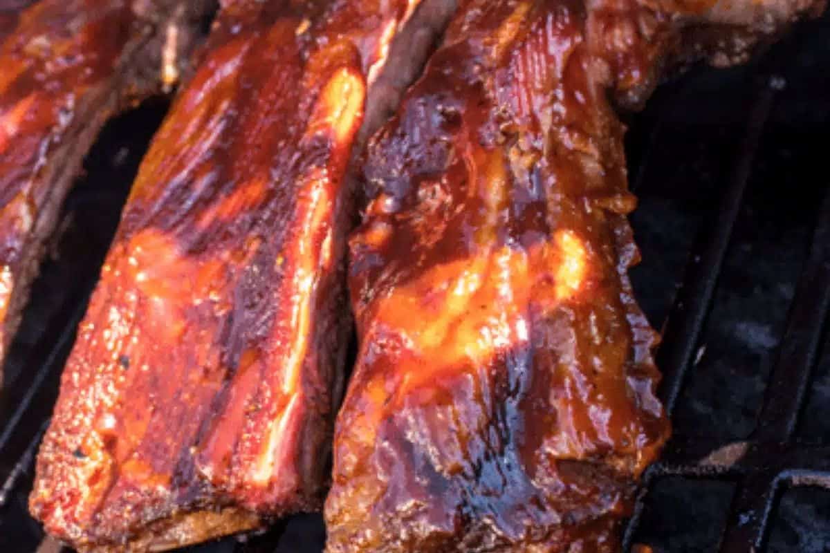 A close-up of some smoked beef ribs with sweet chili dry rub, pictured on a grill rack.