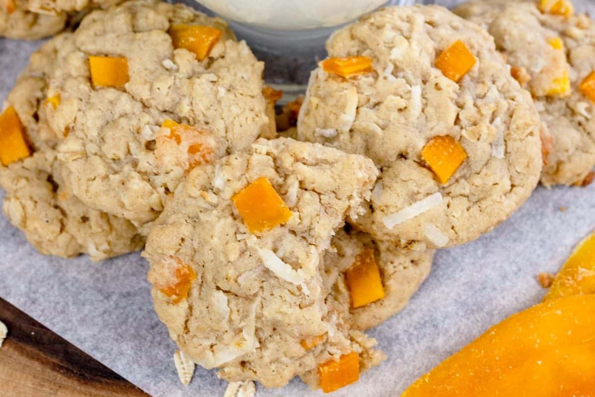 Close-up of some tropical mango cookies, topped with mango chunks amd coconut flakes.