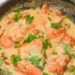 Fish in a creamy sauce with spinach and chopped parsley, cooked to perfection in a skillet.