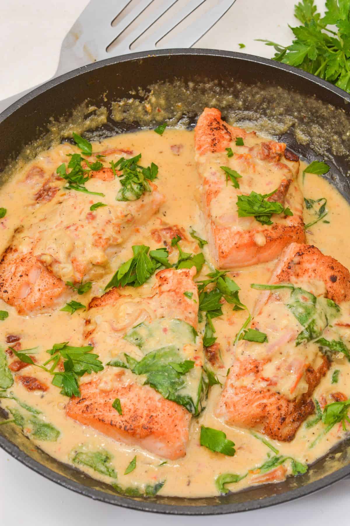 Fish in a creamy sauce with spinach and chopped parsley, cooked to perfection in a skillet.