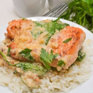 Tuscan Salmon fillet grilled to perfection, topped with creamy spinach sauce and fresh parsley, served on a bed of white rice.