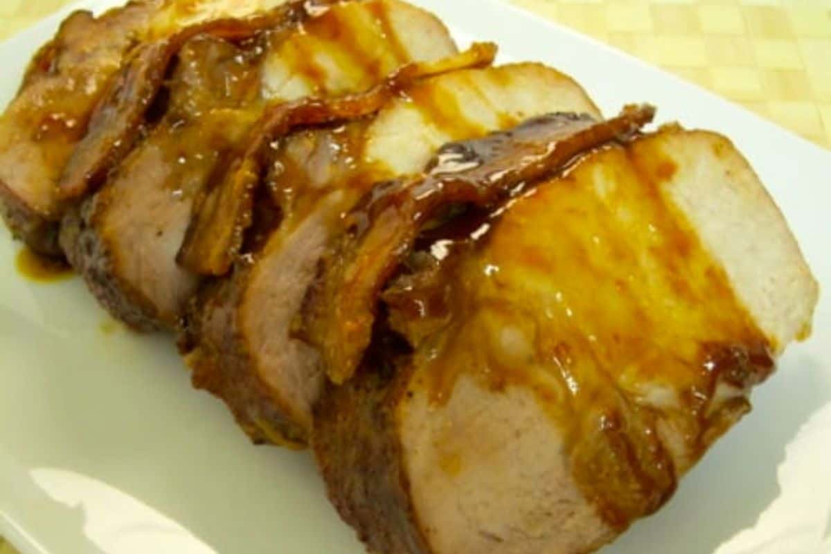 Sliced delicious pork roast topped with a glossy brown sauce, arranged on a white plate—a standout among pork roast recipes.