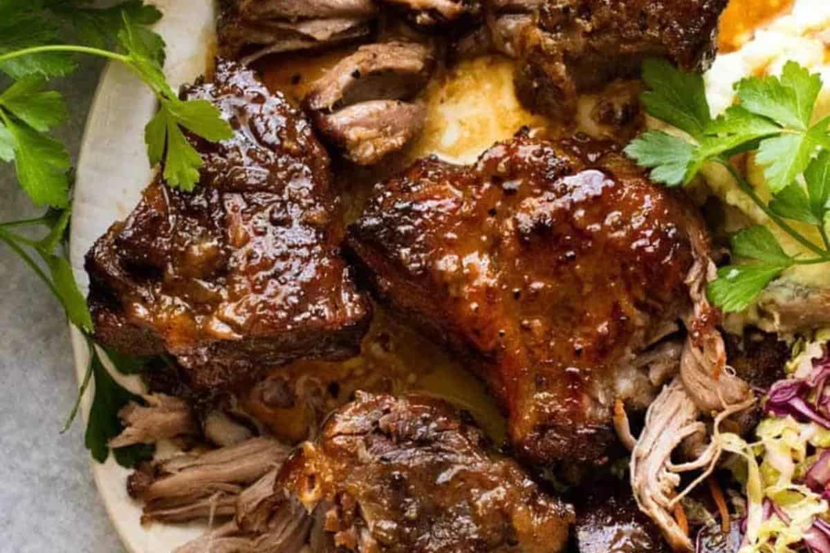 Close-up of braised and glazed beef pieces on a plate, garnished with fresh parsley and served with a side of salad—perfect inspiration for those who love discovering Pork Roast Recipes.