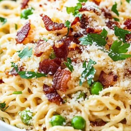 A plate of creamy pasta topped with crispy bacon pieces, green peas, grated cheese, and fresh parsley—an upgrade ramen twist for anyone craving flavor packed comfort food.
