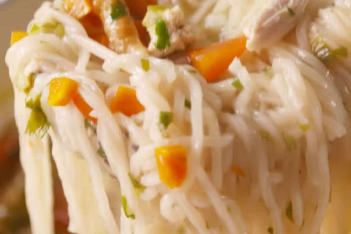 Close-up of cooked ramen noodles mixed with chopped orange vegetables, green herbs, and pieces of chicken—an easy ramen recipe that's flavor packed for a quick and satisfying meal.