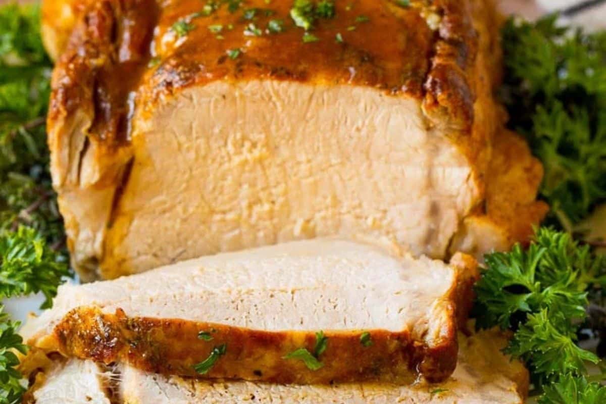 A cooked turkey breast roast is sliced and garnished with fresh parsley, perfect alongside your favorite pork roast recipes.