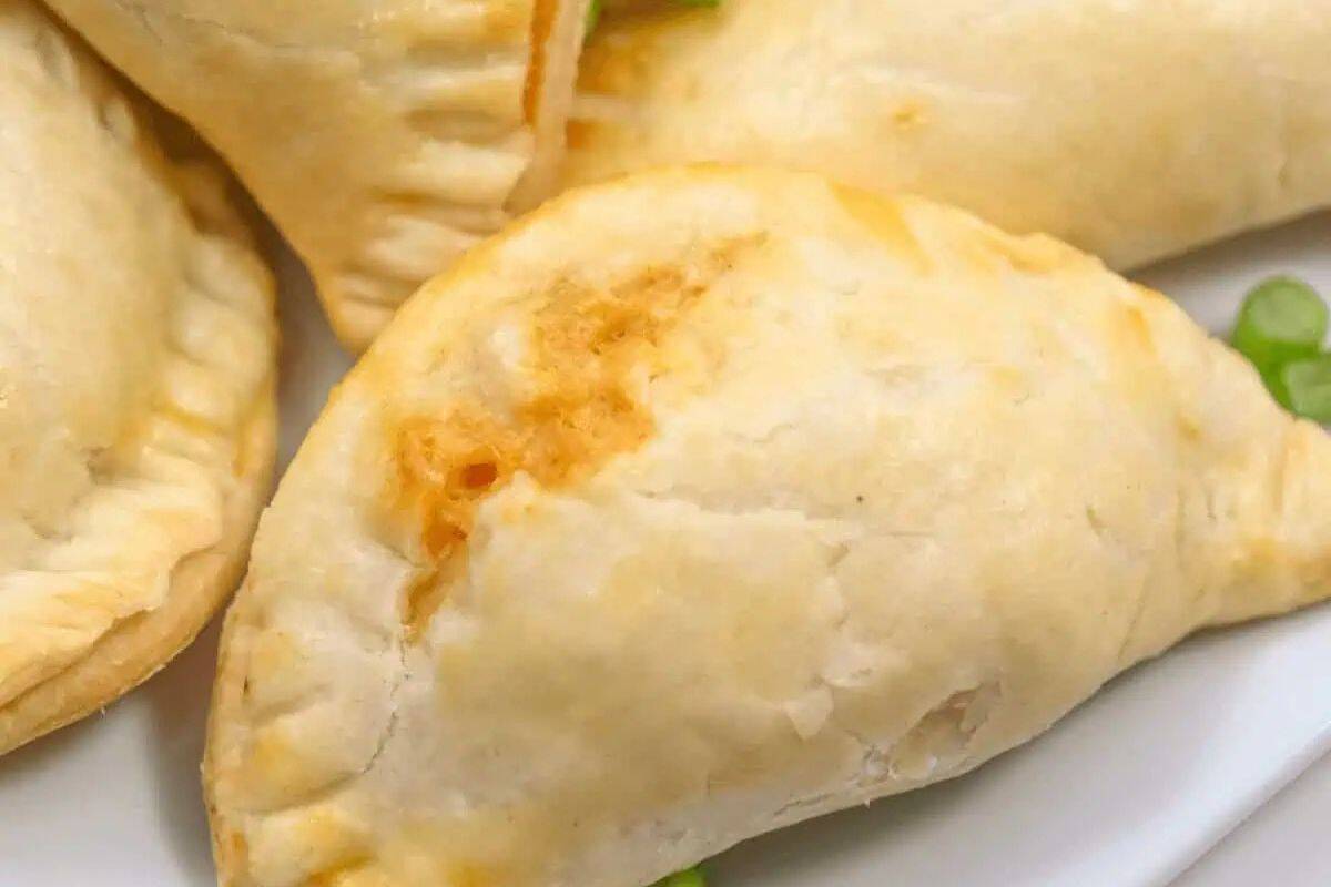 Close-up of baked empanadas with golden crust, arranged on a white plate—perfect for adding to your party food recipes collection.