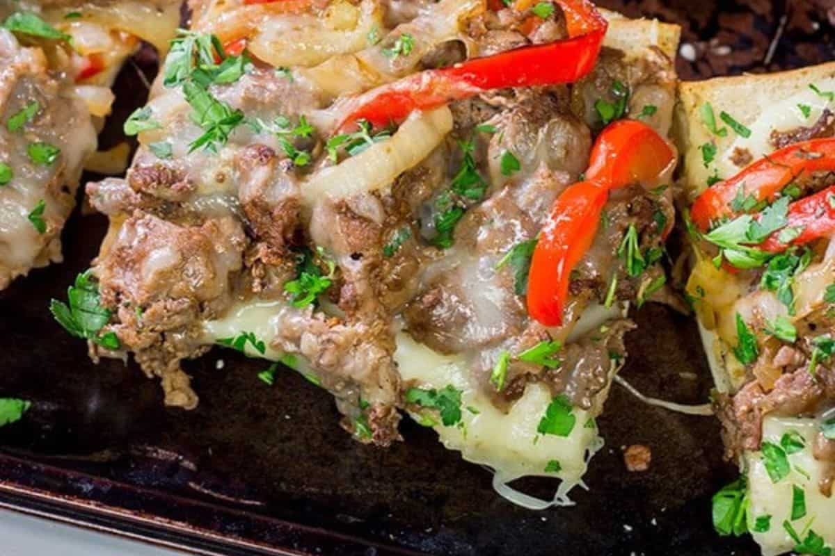  Slices of garlic bread topped with melted cheese, steak or ground meat, sautéed onions, red bell pepper strips, and chopped fresh parsley.