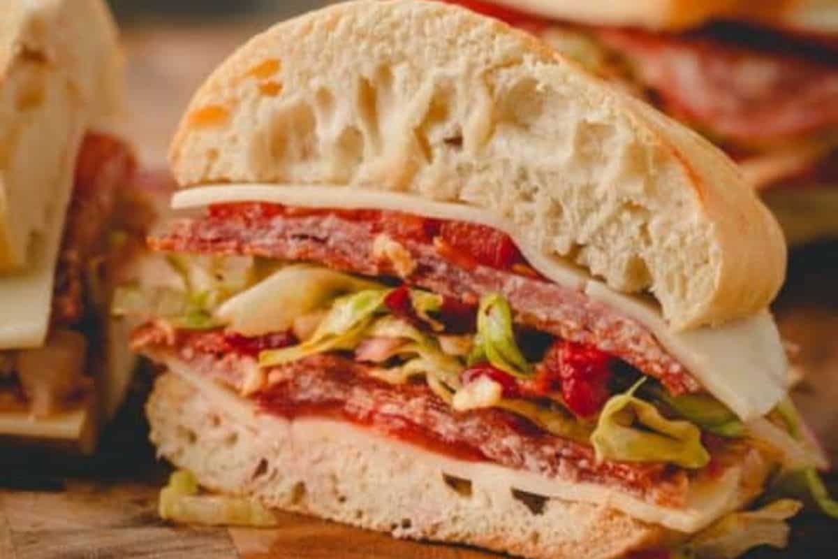 A close-up of a delicious sandwich with sliced bread, layers of deli meat, cheese, lettuce, and tomato—perfect for fans of gourmet sandwiches.