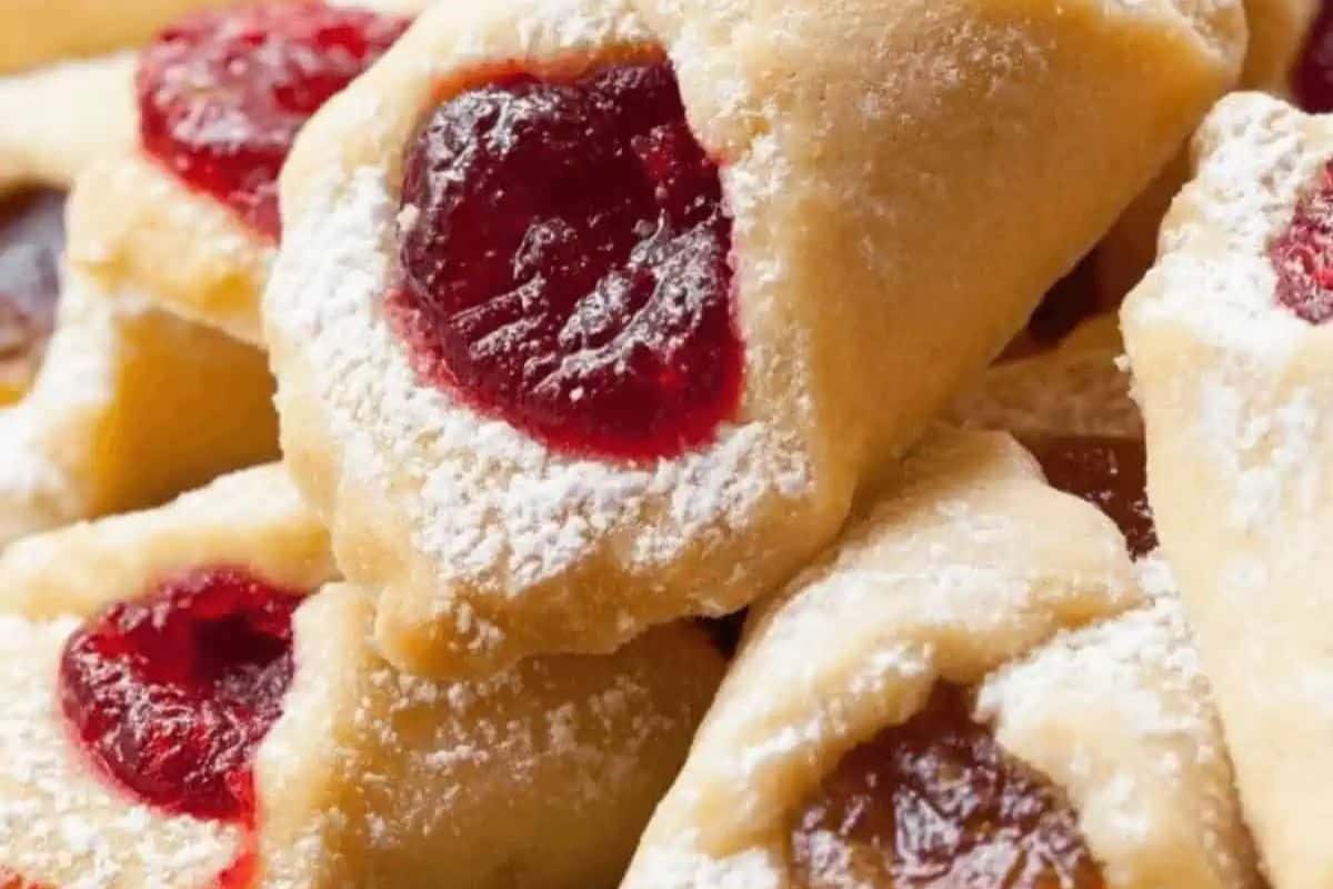 Traditional Polish Kolaczki cookies—delicate, flaky pastries filled with fruit jam and dusted with powdered sugar.