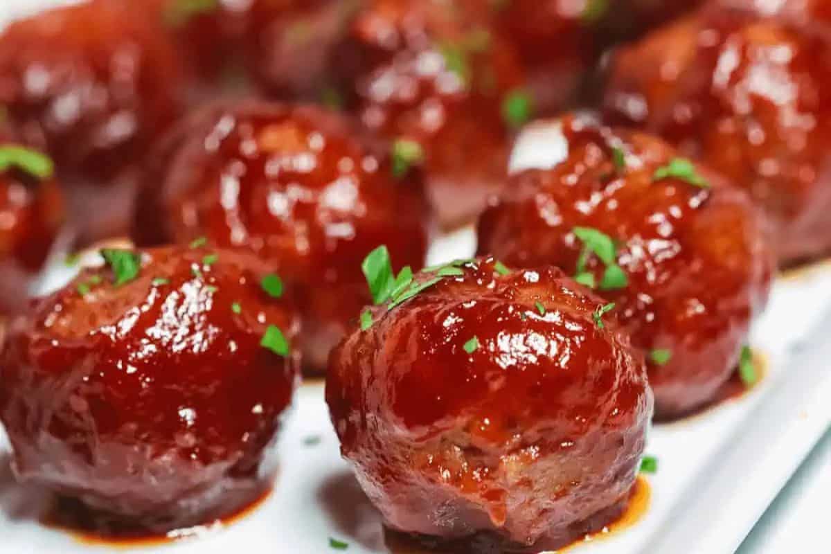 Close-up of glazed meatballs garnished with chopped herbs, arranged on a white serving platter—perfect for your next gathering and ideal for party food recipes.