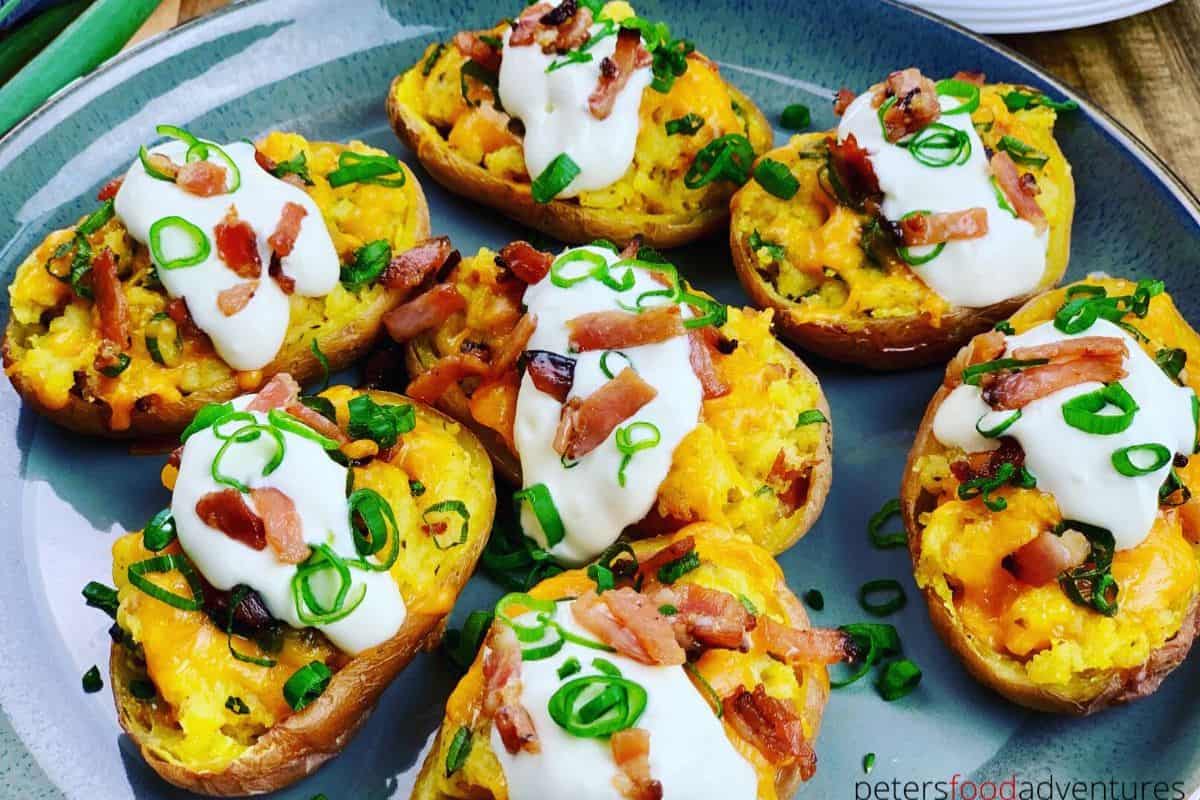 Twice-baked potato halves topped with sour cream, chopped bacon, and sliced green onions make a crowd-pleasing addition to your party food recipes, served beautifully on a gray plate.