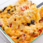 A close-up of the dish with cheesy bowtie pasta, black beans, and diced tomatoes in a glass baking dish.