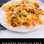 A plate of Enchilada Pasta baked to perfection, topped with melted cheese and herbs, sits in front of a baking dish and gray cloth in the background.