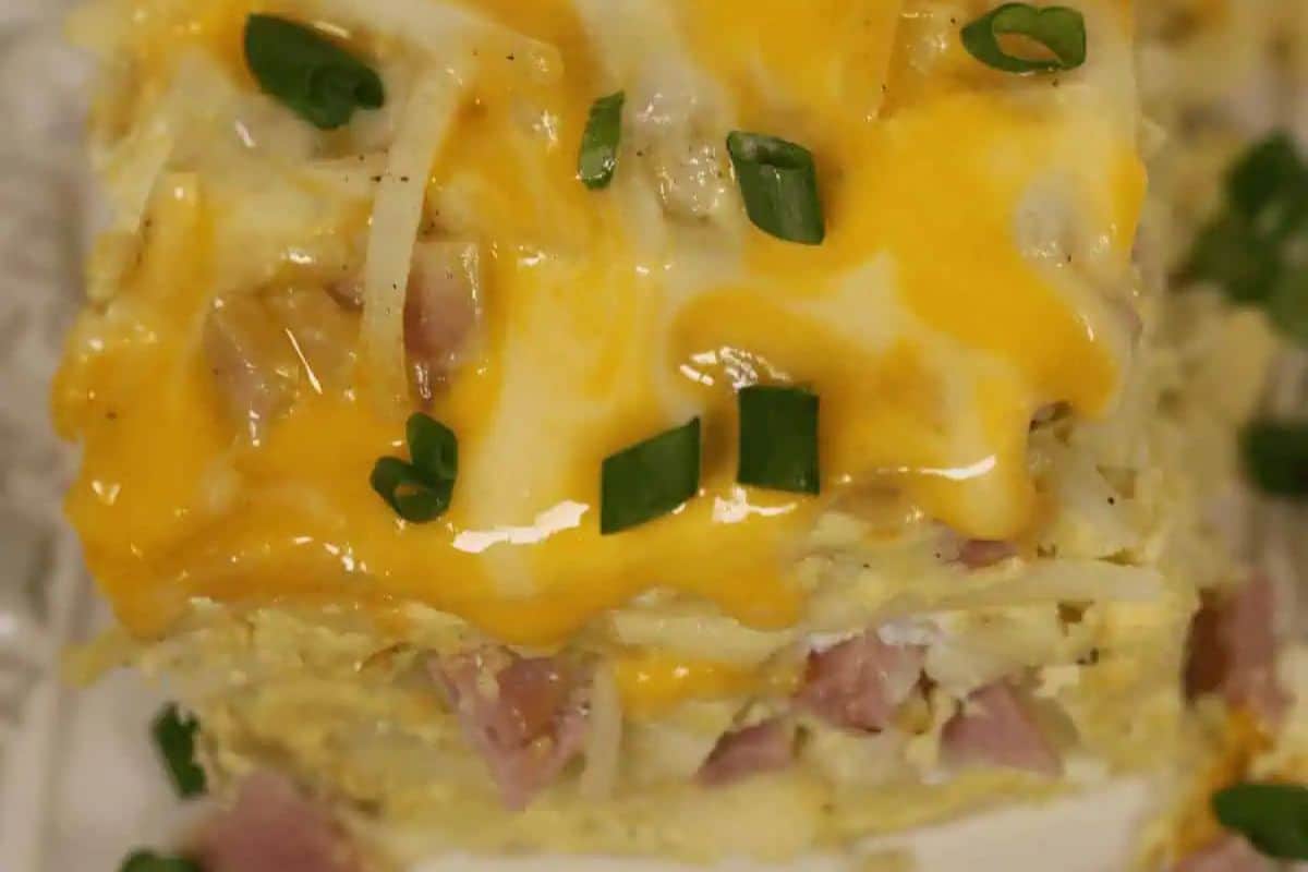 Close-up of a baked casserole topped with melted cheddar cheese, chopped green onions, and diced ham—perfect for a cozy Christmas morning or as a delicious addition to your favorite holiday breakfast spread.