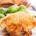 A golden breadcrumbs on a white plate, served with brussels sprouts in the background.