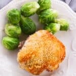 A plate with Hellman's Crusted Parmesan Chicken thigh, baked to perfection, and a serving of steamed Brussels sprouts.