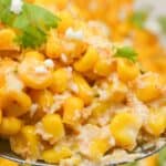 A close-up of a spoonful of Mexican Street Corn Casserole, featuring corn kernels mixed with creamy dressing, cheese, and garnished with cilantro.