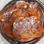 A silver plate with several slices of Pumpkin Pie Spice French Toast topped with powdered sugar.