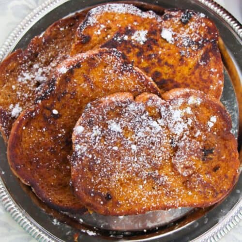 A silver plate with several slices of Pumpkin Pie Spice French Toast topped with powdered sugar.