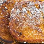 Close-up of Pumpkin Pie Spice French Toast slices dusted with powdered sugar on a silver plate.