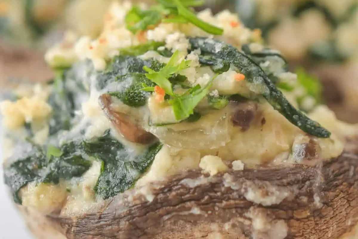 Close-up of a stuffed mushroom topped with creamy spinach filling, breadcrumbs, and chopped herbs—a delicious addition to your favorite stuffed mushroom recipes.