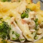 A close-up of a spoonful of penne garnished with chopped parsley.